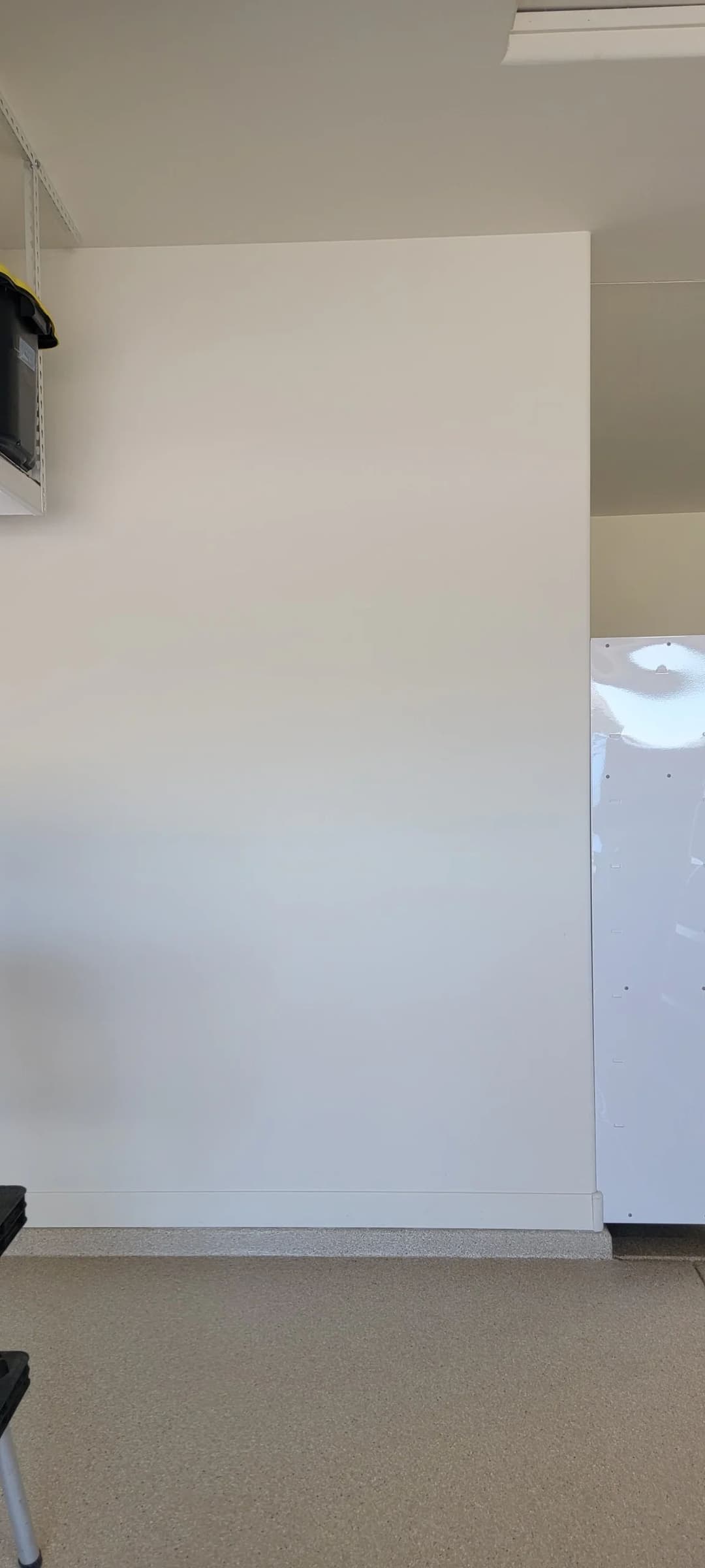 Empty workspace with a clean white wall and a refrigerator in a modern setting.