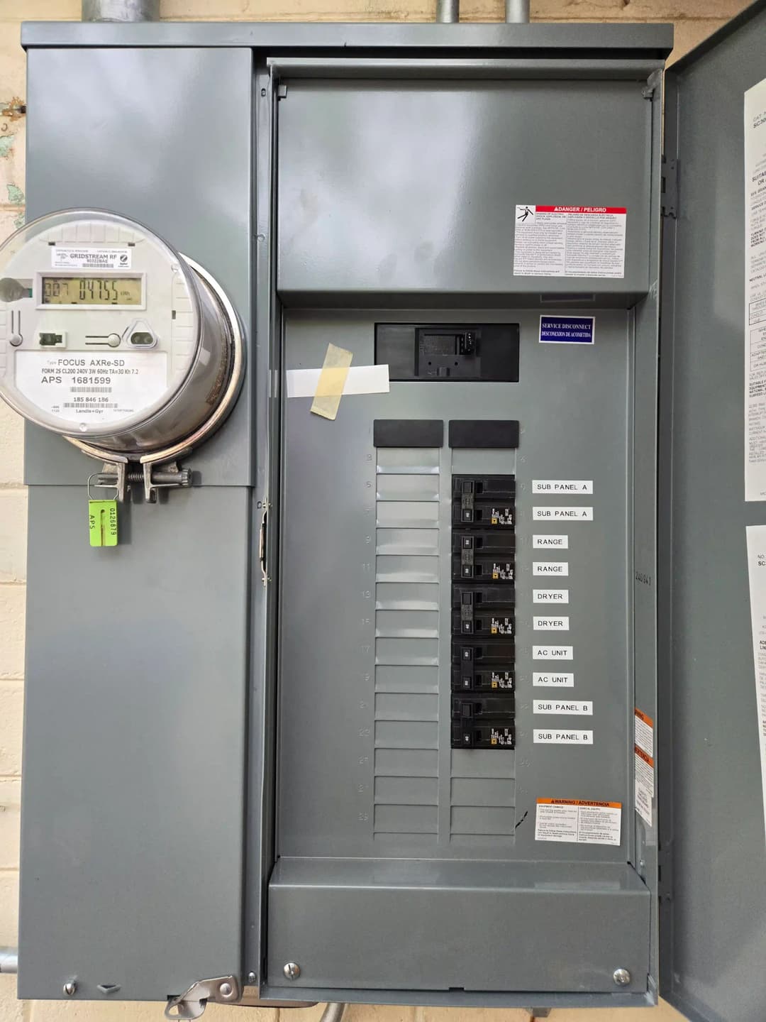 Electrical panel with circuit breakers and a utility meter on a beige wall.
