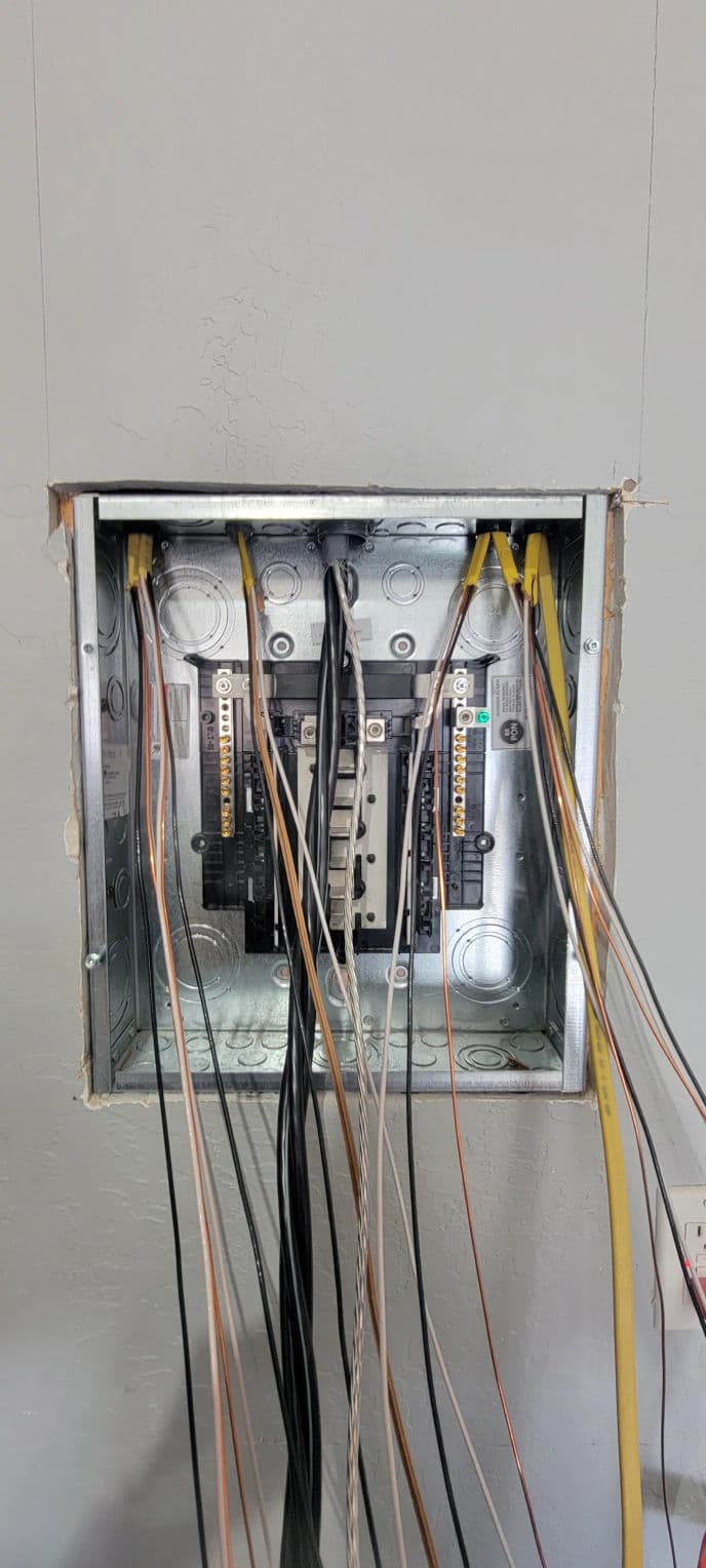 Electrical circuit breaker panel with exposed wires and connections.