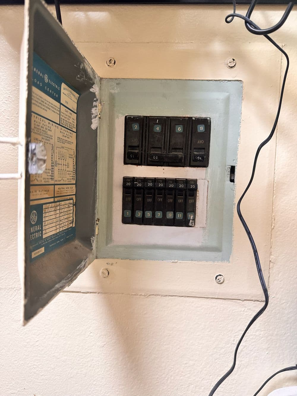 Electrical service panel with labeled circuit breakers and wiring visible.