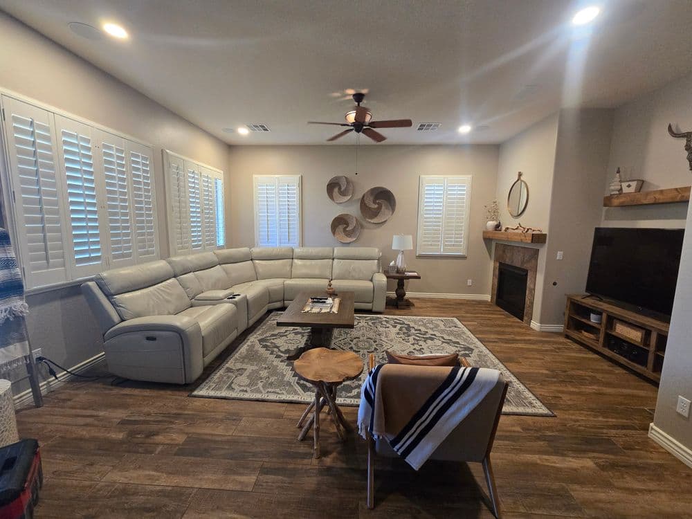 Modern living room with a large sectional sofa, hardwood flooring, and decorative wall accents.
