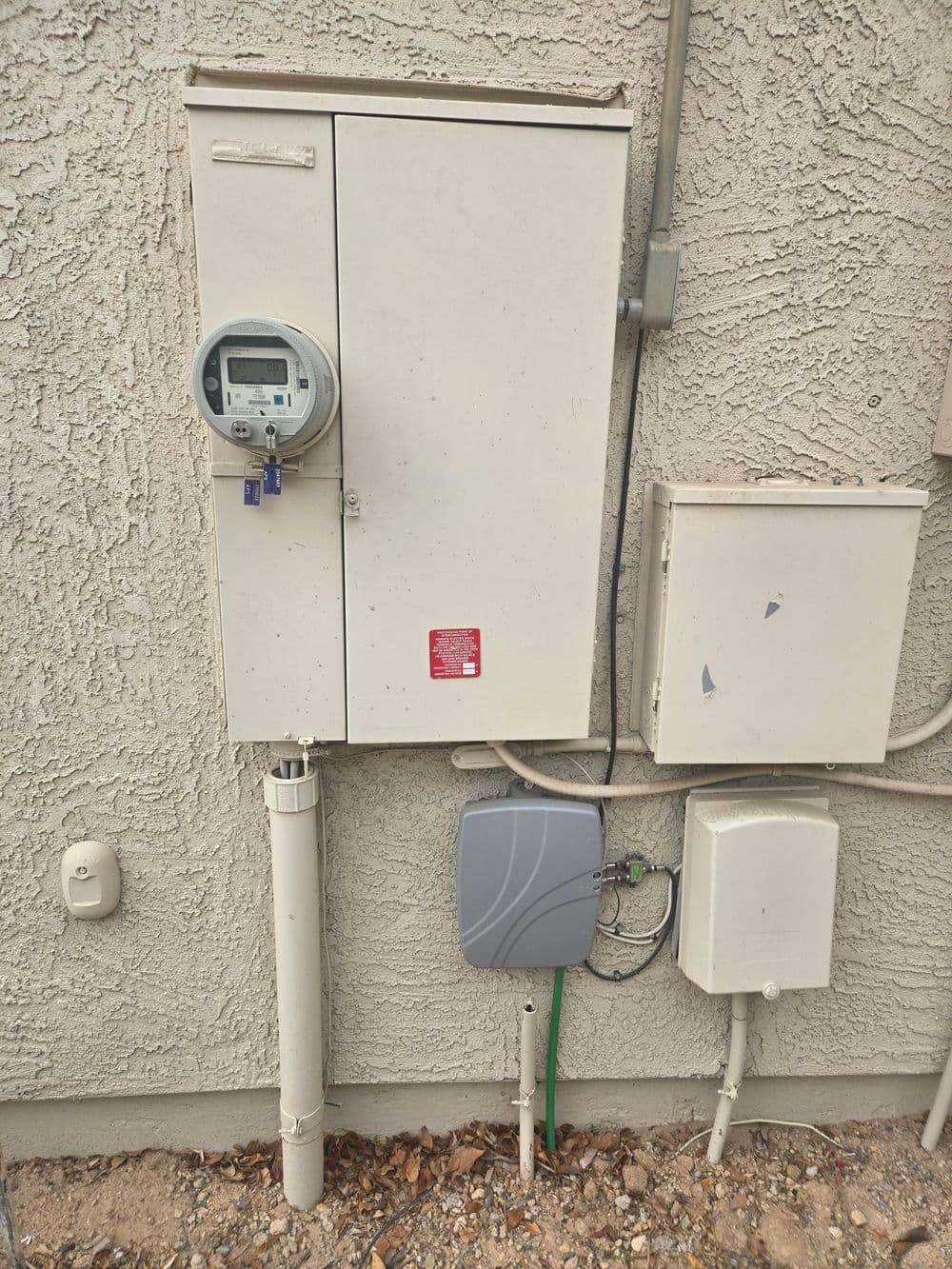 Utility meter box on exterior wall with digital meter and connecting equipment.