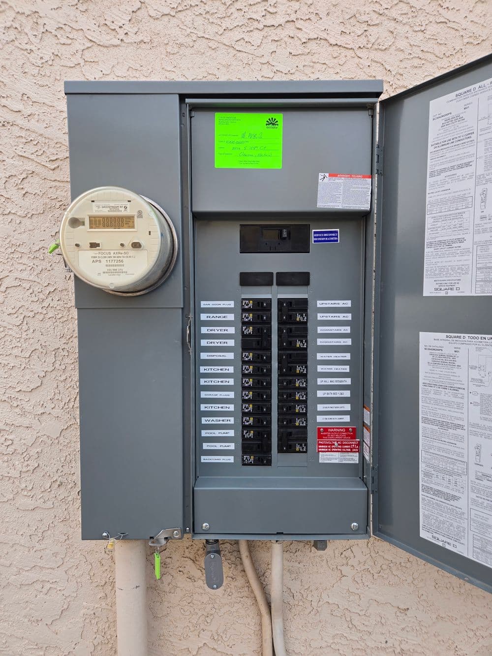 Electrical panel with circuit breakers and utility meter on textured wall.