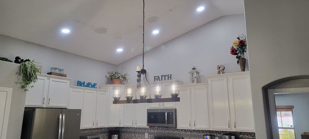 Modern kitchen with white cabinets, pendant lighting, and decorative accents on shelves.